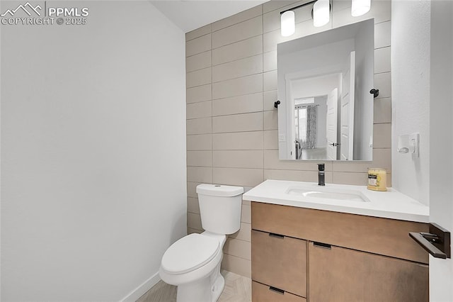 bathroom with vanity, toilet, and tile walls