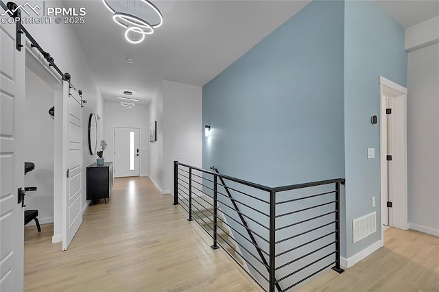 hall featuring an inviting chandelier and light hardwood / wood-style flooring