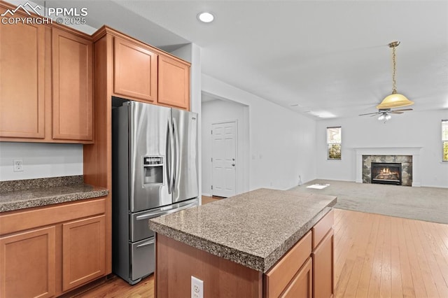 kitchen featuring stainless steel fridge, light hardwood / wood-style floors, ceiling fan, and a kitchen island