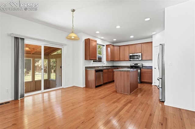 kitchen with pendant lighting, light wood-type flooring, a center island, and appliances with stainless steel finishes