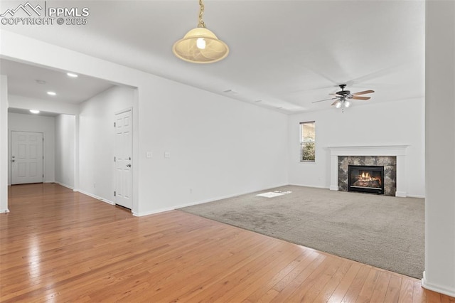 unfurnished living room featuring wood-type flooring, ceiling fan, and a fireplace