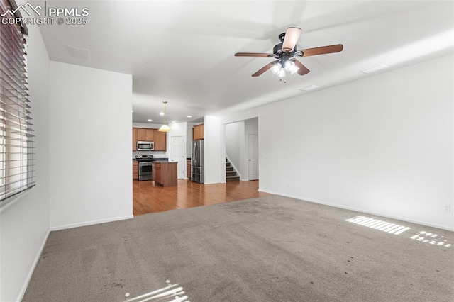 unfurnished living room with light colored carpet and ceiling fan