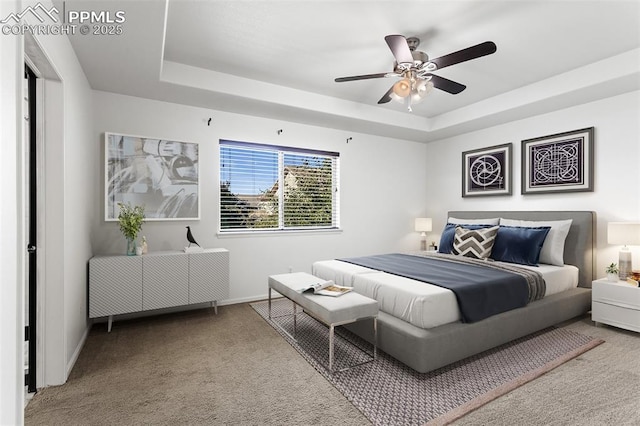 bedroom with a raised ceiling, carpet, and ceiling fan