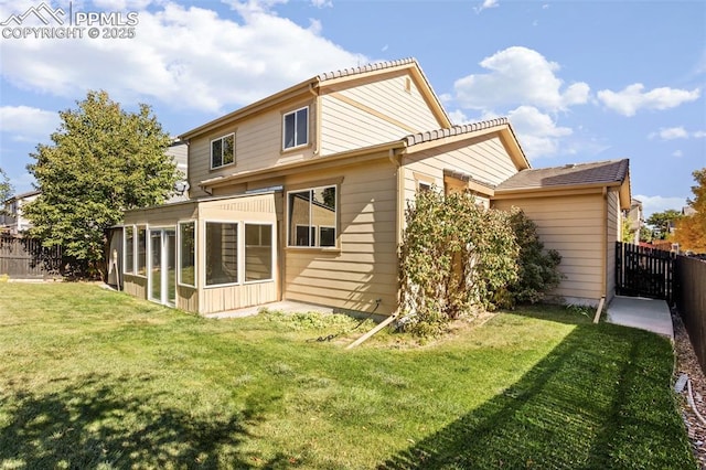 rear view of house with a yard and a sunroom