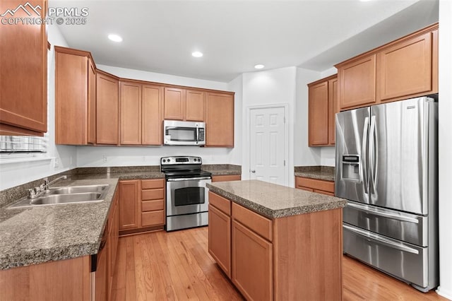 kitchen with a kitchen island, appliances with stainless steel finishes, sink, and light wood-type flooring