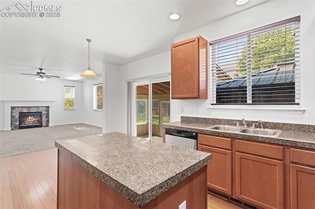 kitchen with a tile fireplace, a kitchen island, dishwasher, sink, and hanging light fixtures