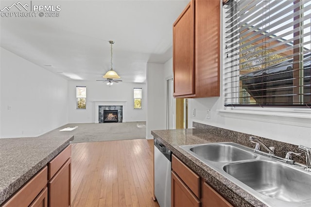 kitchen featuring pendant lighting, sink, ceiling fan, a high end fireplace, and stainless steel dishwasher