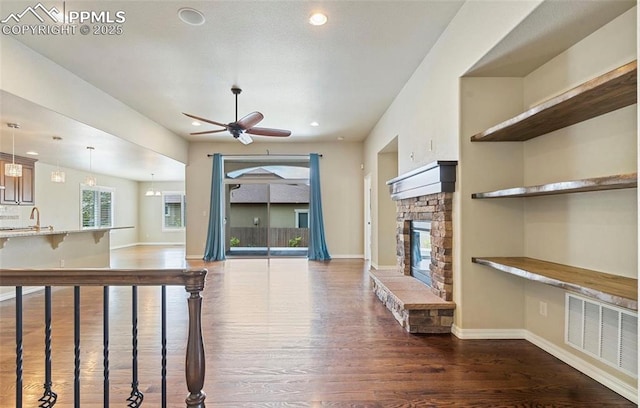 unfurnished living room with dark hardwood / wood-style floors, ceiling fan, sink, and a fireplace