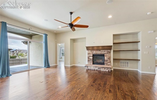 unfurnished living room featuring a fireplace, built in shelves, ceiling fan, and hardwood / wood-style floors