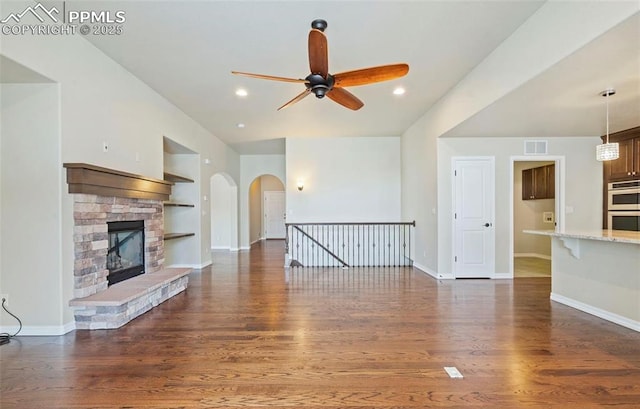 unfurnished living room featuring a fireplace, dark hardwood / wood-style flooring, built in features, and ceiling fan