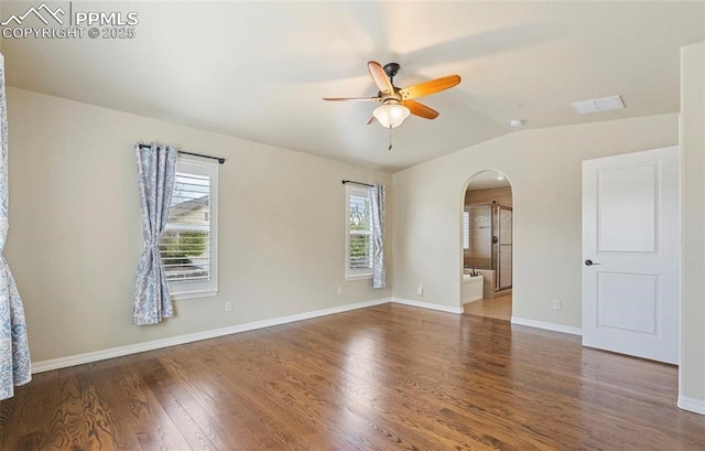 unfurnished room with vaulted ceiling, ceiling fan, a healthy amount of sunlight, and dark hardwood / wood-style floors