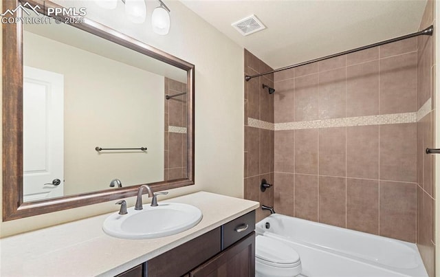 full bathroom with vanity, tiled shower / bath combo, and toilet