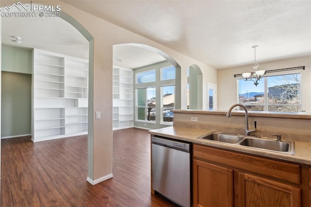 kitchen with built in shelves, sink, hanging light fixtures, stainless steel dishwasher, and dark hardwood / wood-style flooring