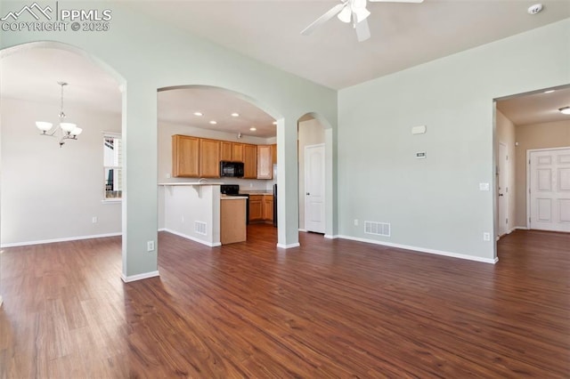 unfurnished living room featuring ceiling fan with notable chandelier and dark hardwood / wood-style floors