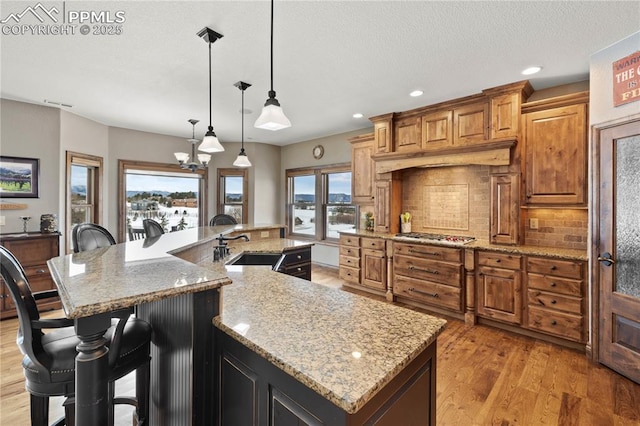 kitchen featuring sink, hanging light fixtures, tasteful backsplash, a spacious island, and a breakfast bar