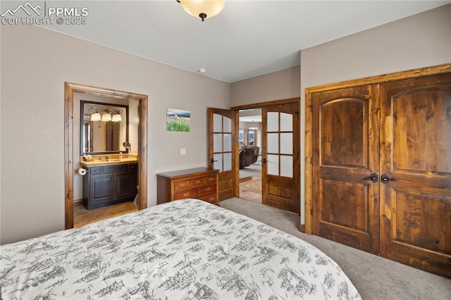 carpeted bedroom with connected bathroom and french doors