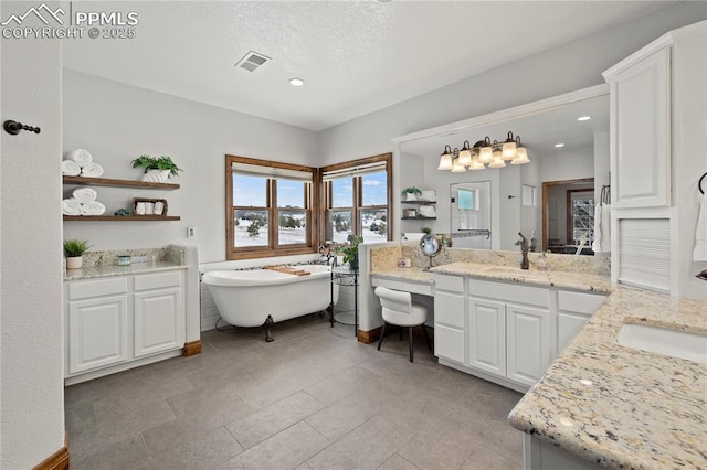 bathroom with a textured ceiling, vanity, a tub to relax in, and tile patterned flooring