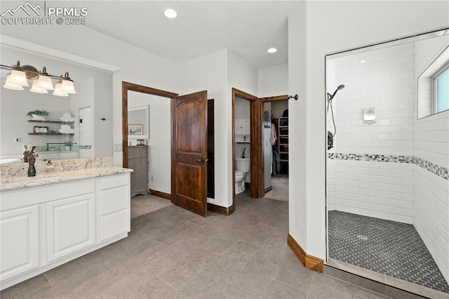 bathroom with toilet, vanity, and tiled shower