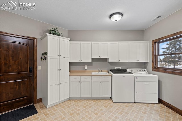 laundry area with cabinets, washing machine and dryer, and sink