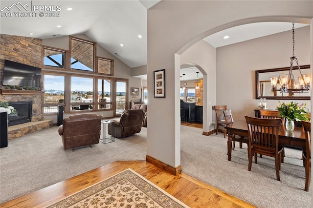 living room featuring a stone fireplace, a wealth of natural light, and a notable chandelier