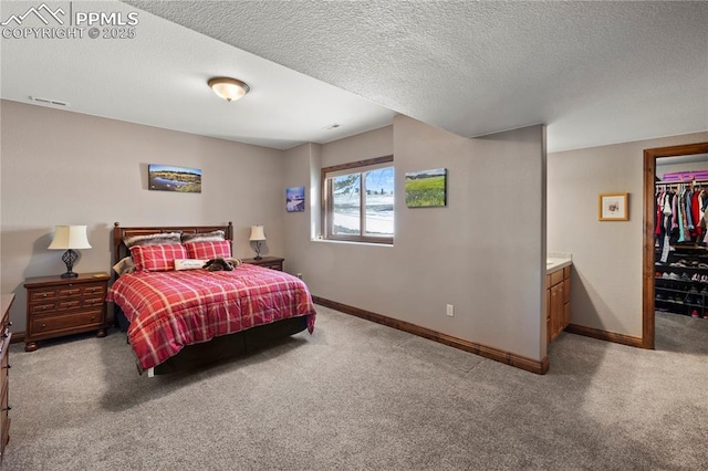 carpeted bedroom with a closet, a textured ceiling, and ensuite bath