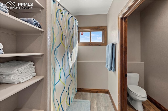 bathroom featuring wood-type flooring, toilet, and walk in shower