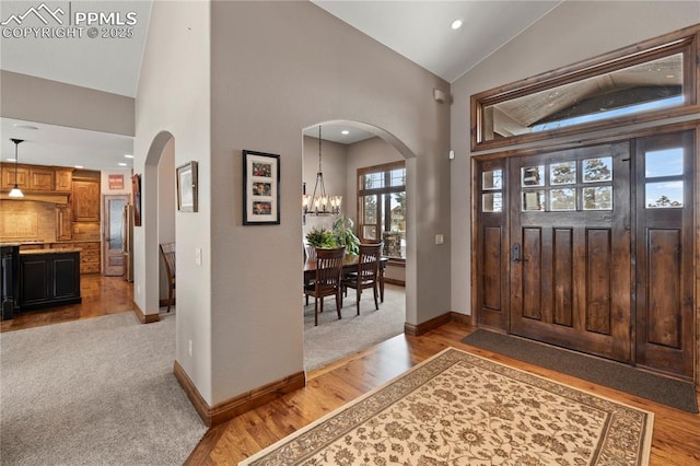 foyer entrance with high vaulted ceiling, a chandelier, and light wood-type flooring