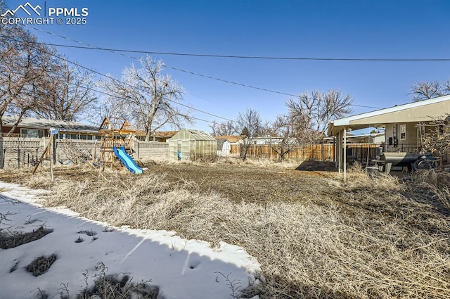 snowy yard with a playground and an outdoor structure