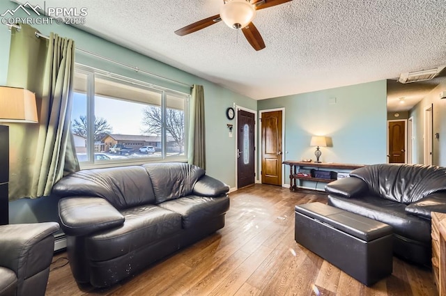 living room with hardwood / wood-style flooring, a textured ceiling, and ceiling fan