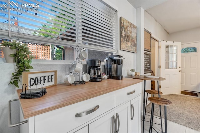 bar featuring white cabinetry, butcher block counters, and light tile patterned flooring