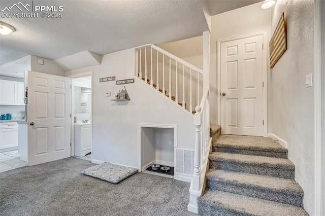 staircase featuring vaulted ceiling, carpet floors, and a textured ceiling