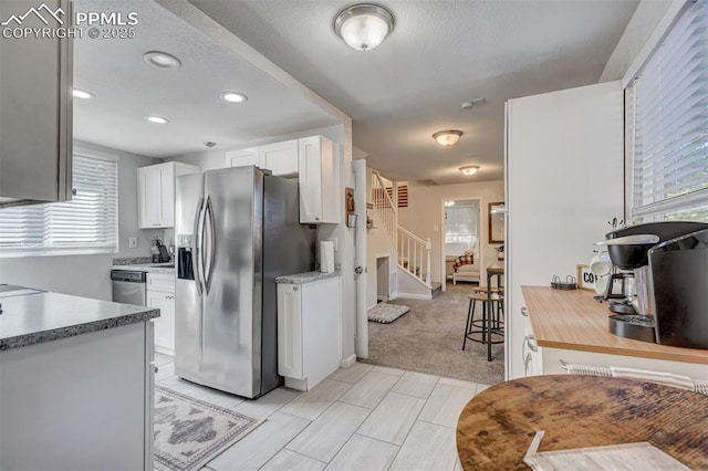 kitchen with white cabinetry, light colored carpet, and stainless steel appliances