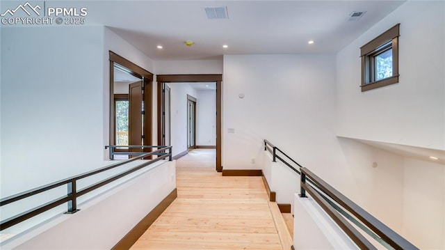 hall featuring a healthy amount of sunlight and light hardwood / wood-style floors