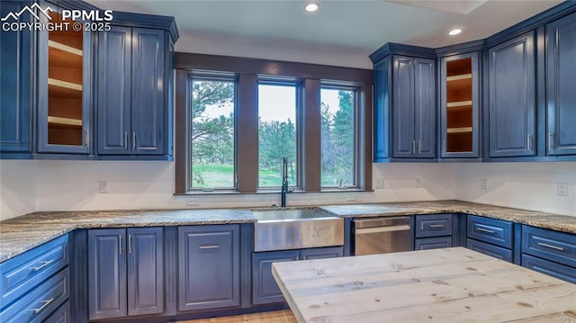 kitchen with light stone counters, blue cabinets, a wealth of natural light, and sink