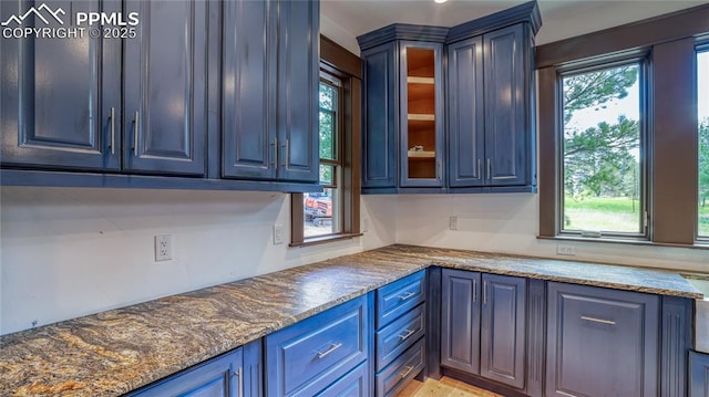 kitchen with blue cabinetry and dark stone counters