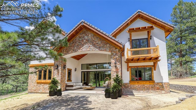 rear view of house with outdoor lounge area, a balcony, and a patio