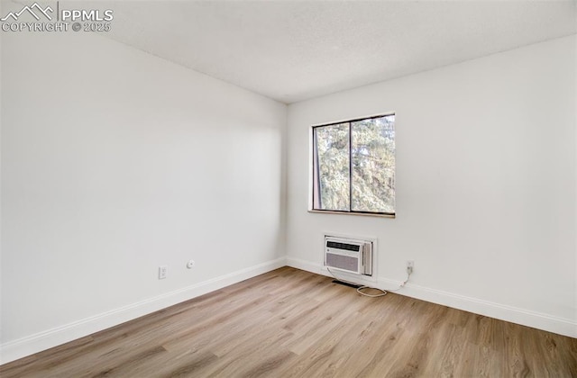 unfurnished room featuring light wood-type flooring and a wall unit AC