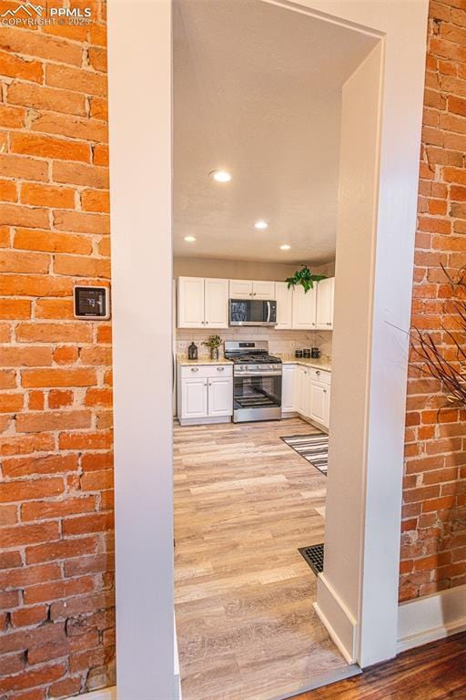 kitchen with white cabinets, light wood-type flooring, and appliances with stainless steel finishes