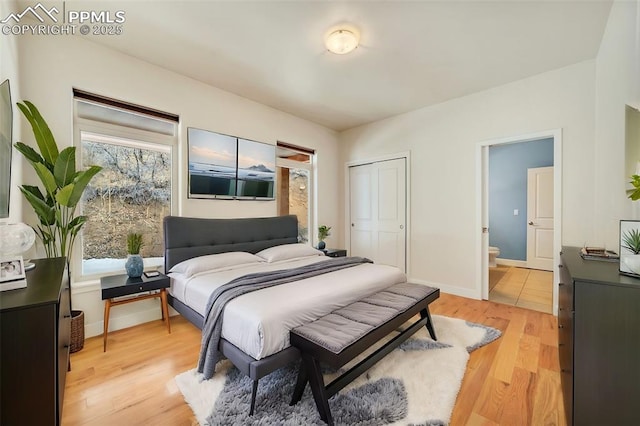 bedroom with ensuite bath, a closet, and light wood-type flooring