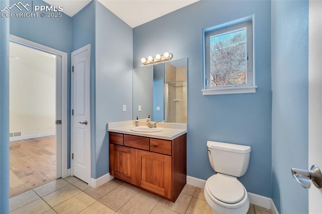 bathroom with tile patterned floors, vanity, toilet, and walk in shower