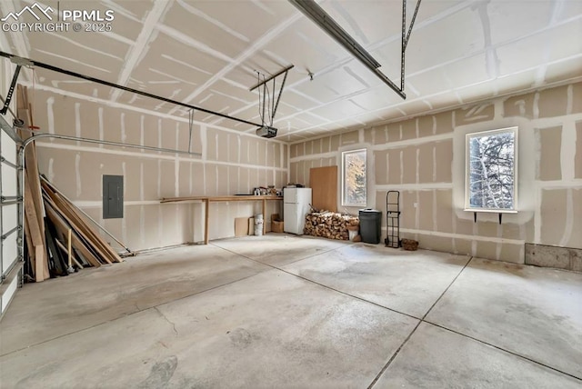 garage featuring white refrigerator, electric panel, and a garage door opener