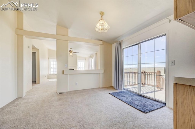 unfurnished living room with ceiling fan, light colored carpet, and lofted ceiling