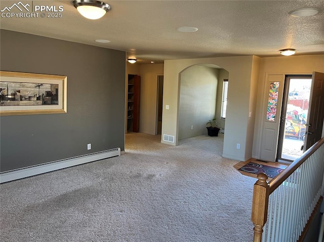 foyer featuring a textured ceiling, carpet flooring, and a baseboard heating unit