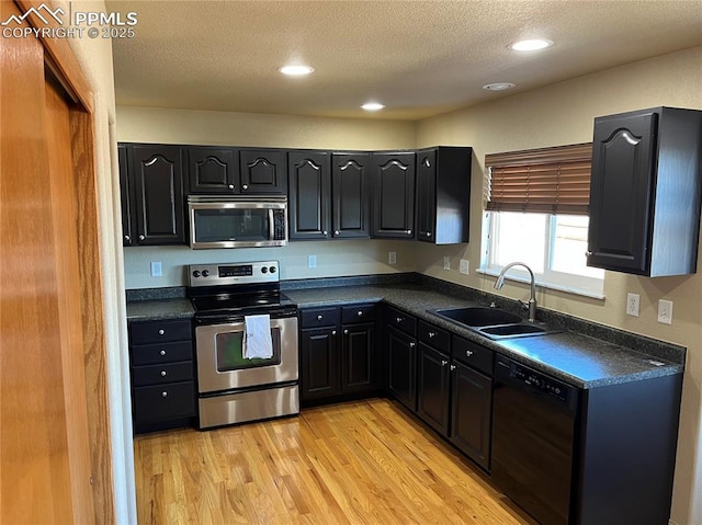 kitchen featuring sink, a textured ceiling, light hardwood / wood-style flooring, and appliances with stainless steel finishes