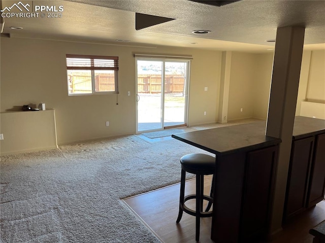 kitchen with a textured ceiling, carpet floors, and a breakfast bar