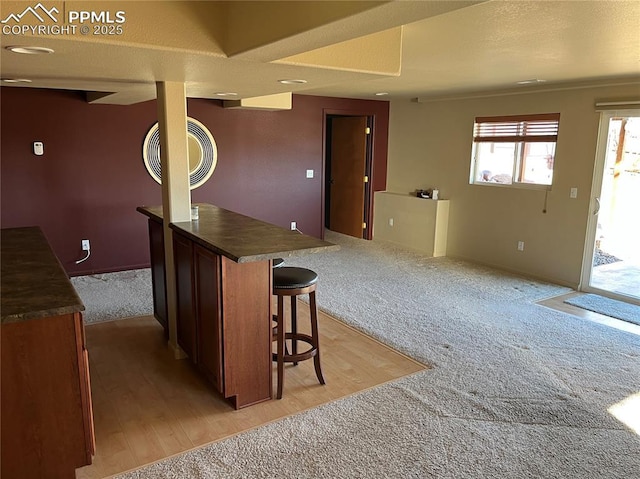 kitchen with a breakfast bar area and light colored carpet