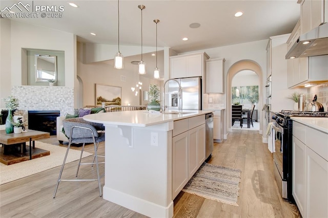 kitchen with decorative backsplash, sink, pendant lighting, stainless steel appliances, and a center island with sink