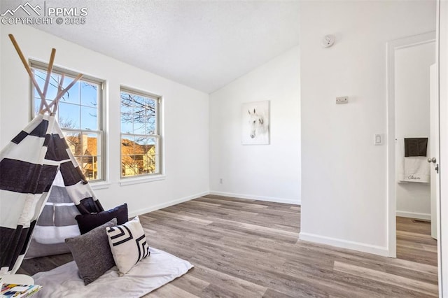 unfurnished room with hardwood / wood-style floors, lofted ceiling, and a textured ceiling