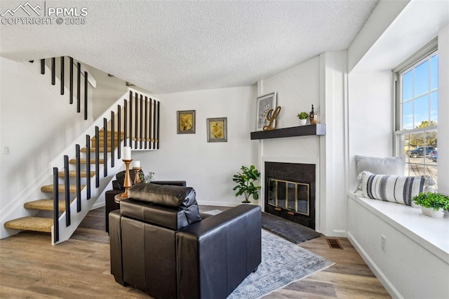 living room featuring a textured ceiling, a fireplace, and wood-type flooring