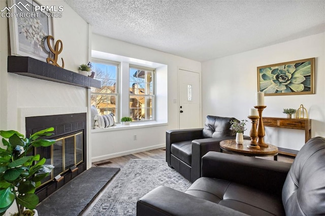 living room with light wood-type flooring, a premium fireplace, and a textured ceiling